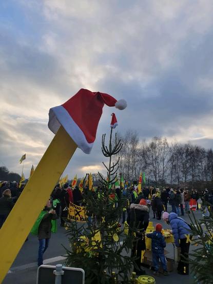 Weihnachtlich dekorierte Demo, u.a.mit roten Nikolausmützen und mit Anti-Atomkraft-Deko geschmückten Weihnachtsbäumen.