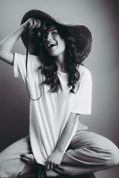 Mujer morena con sombrero y cámara de fotos.