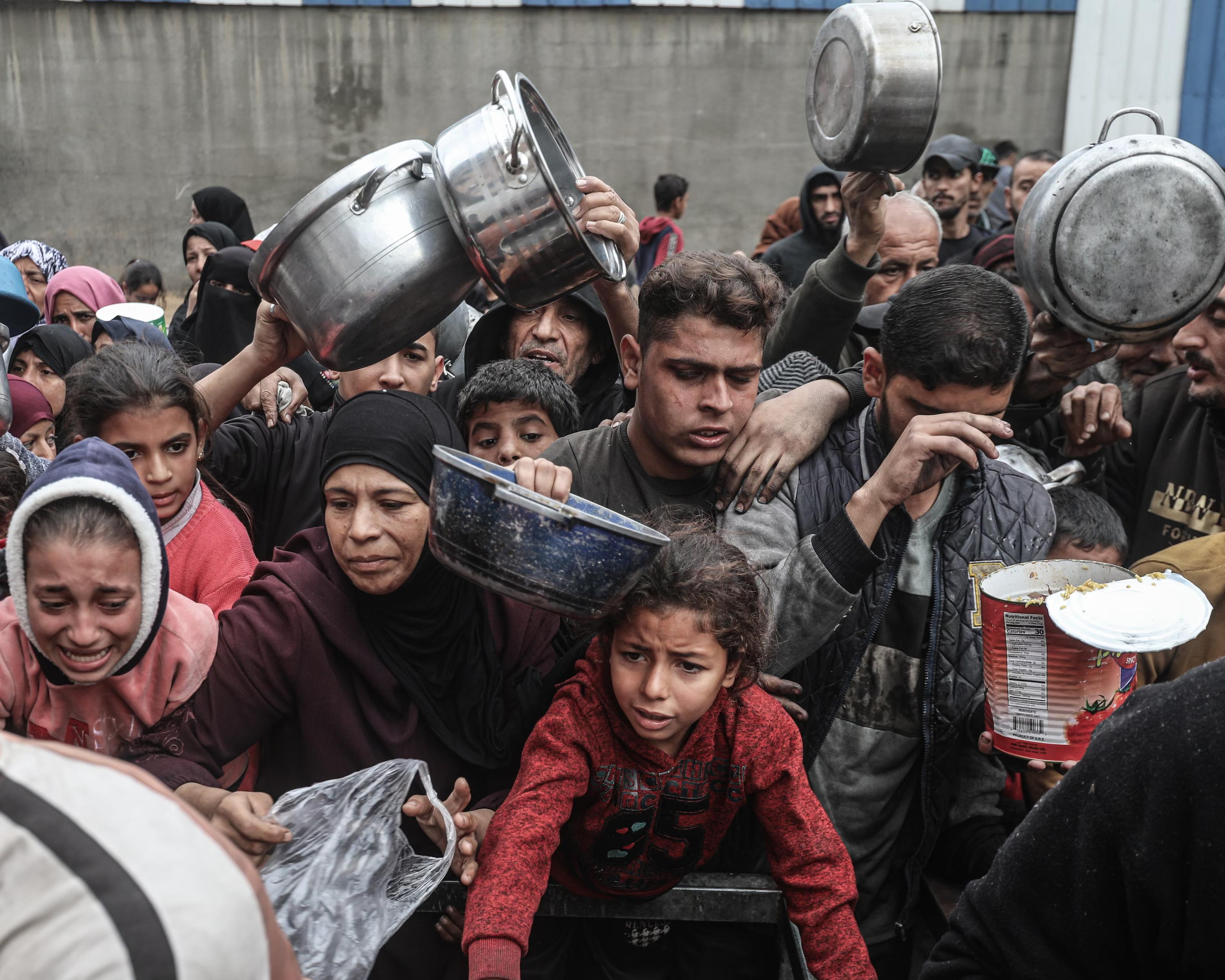 Displaced Palestinians receive meals distributed by a charity.
