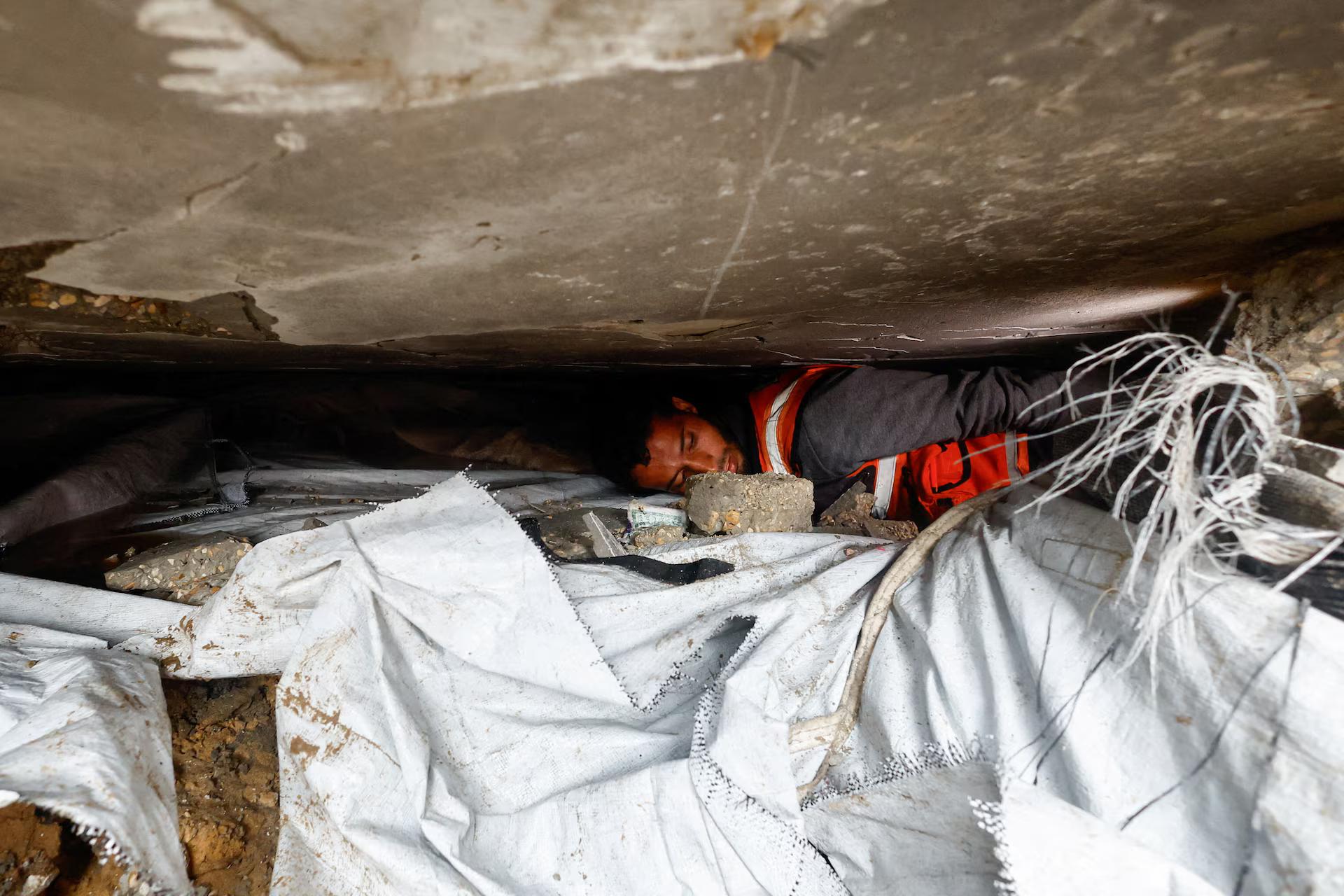 A member of the Palestinian Civil Defence participates in a search and rescue operation in a destroyed house that collapsed amid heavy rains.