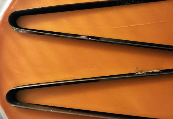 Muster, das einem M ähnlich ist. Oranges Plastik im Hintergrund 