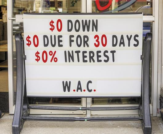 A promotional sign outside a store advertises a financing deal with zero down payment, nothing due for 30 days, and zero percent interest