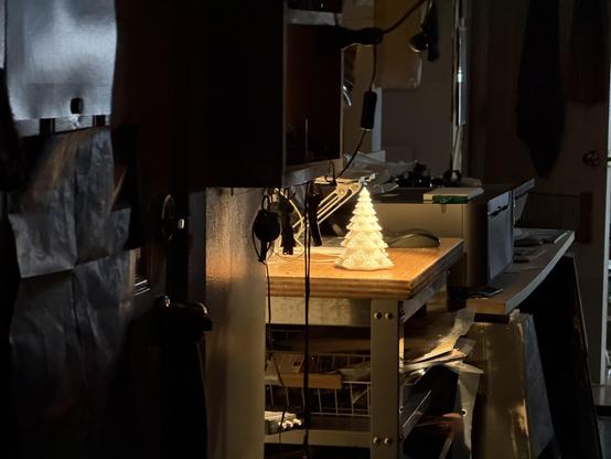 Photo of a small white Christmas tree sitting on a desk from afar