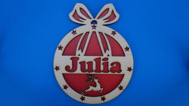 Rundes Weihnachtsornament aus hellem Holz mit großer Schleife oben, Sternendekor, Rentier und personalisiertem Namen Julia. Die Rückseite ist rot hinterlegt.