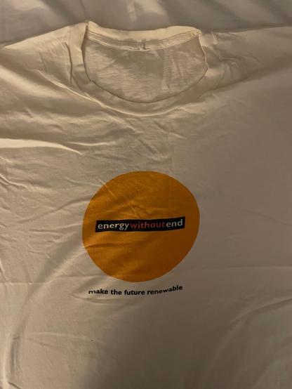 Photograph of the front of a Friends of the Earth t-shirt from the mid-1990s. A bright orange circle contains the words, “energy without end” and underneath text, “make the future renewable”