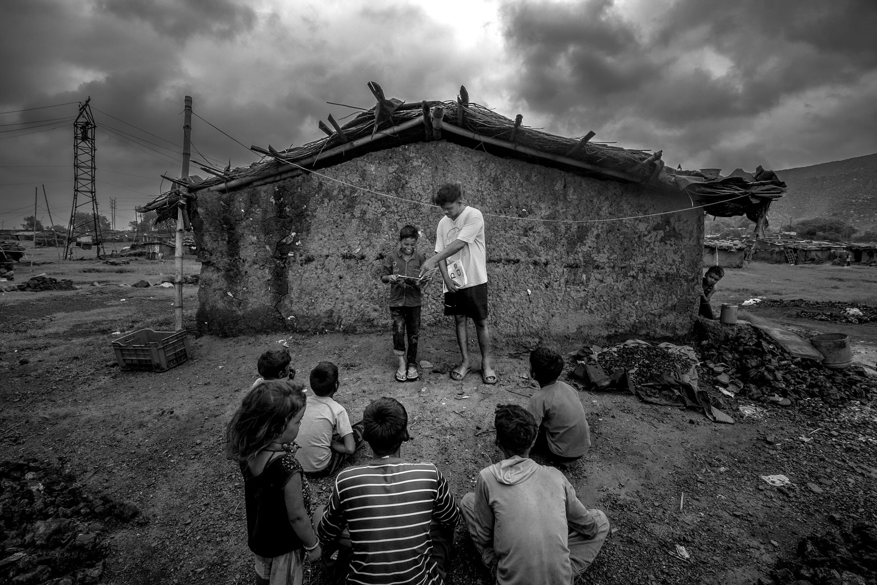 Children sit on the ground in an outside "classroom."