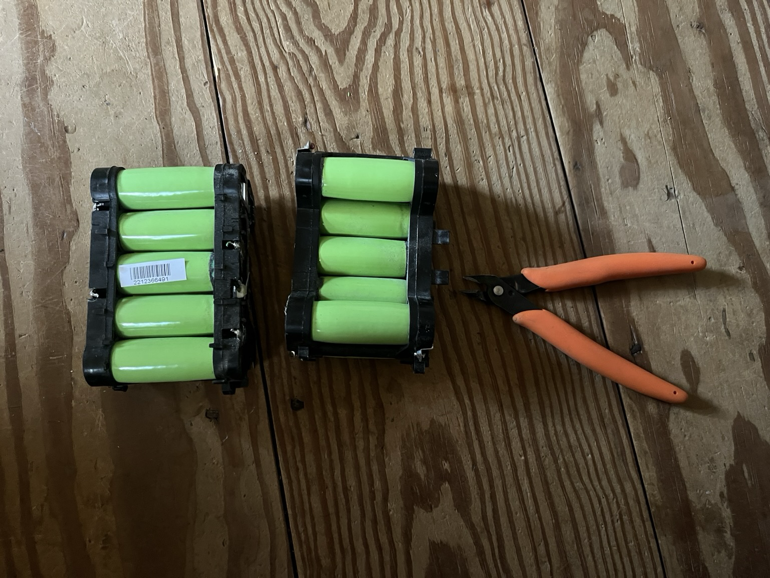 Lithium ion cells spot welded to nickel strips in their plastic holders beside a pair of flush cutters