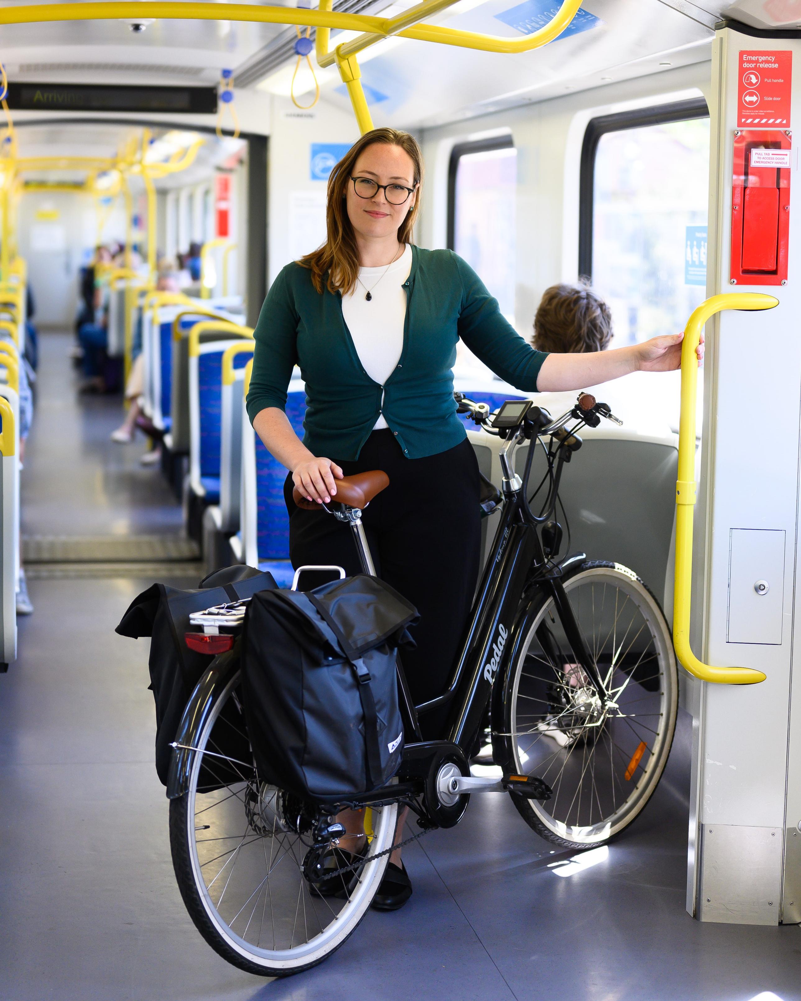 Katherine Copsey MP stands with her eBike on a Melbourne Metro train.