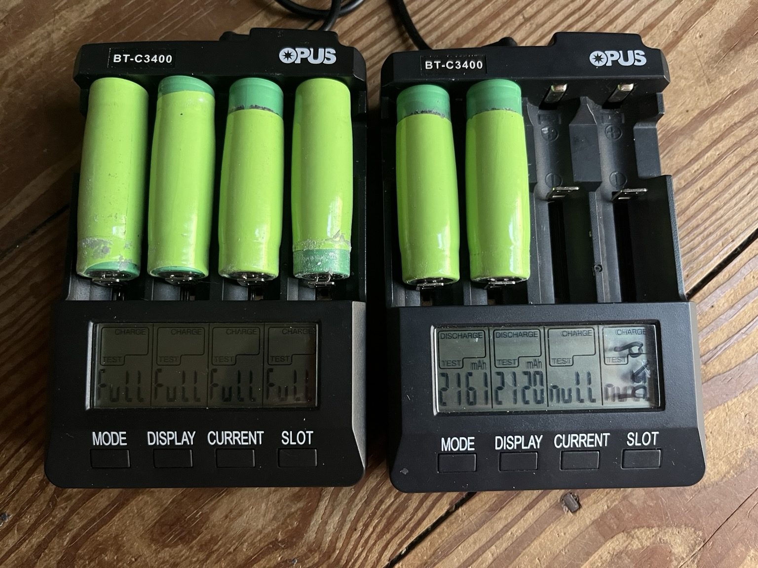 2 lithium ion chargers with 4 slots each holding 6 cells with display showing full charge