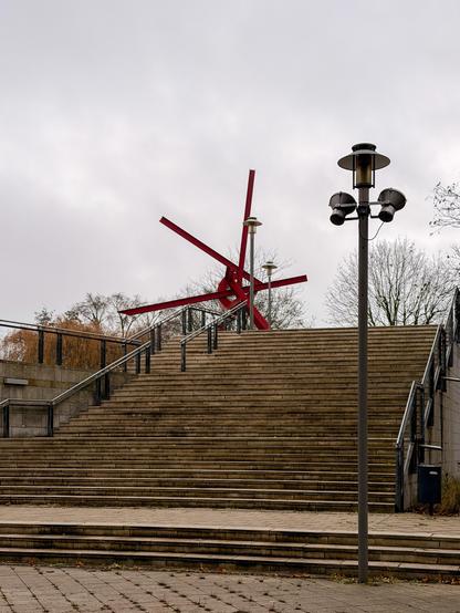 Lange Treppe im hinteren Freibereich des Technoseums Mannheim mit roter Stahlträgerskulptur am oberen Treppenrand