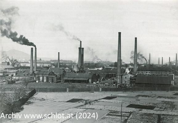 Schwarz-Weiß-Ansicht einer Fabrik mit mehreren Schloten, einer davon mit dunklem Rauch