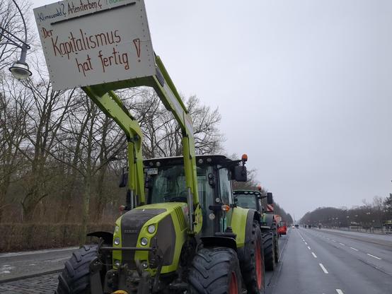 Reihe von Traktoren. Traktor im Vodergrund mit Plakat "Kapitalismus hat fertig!"