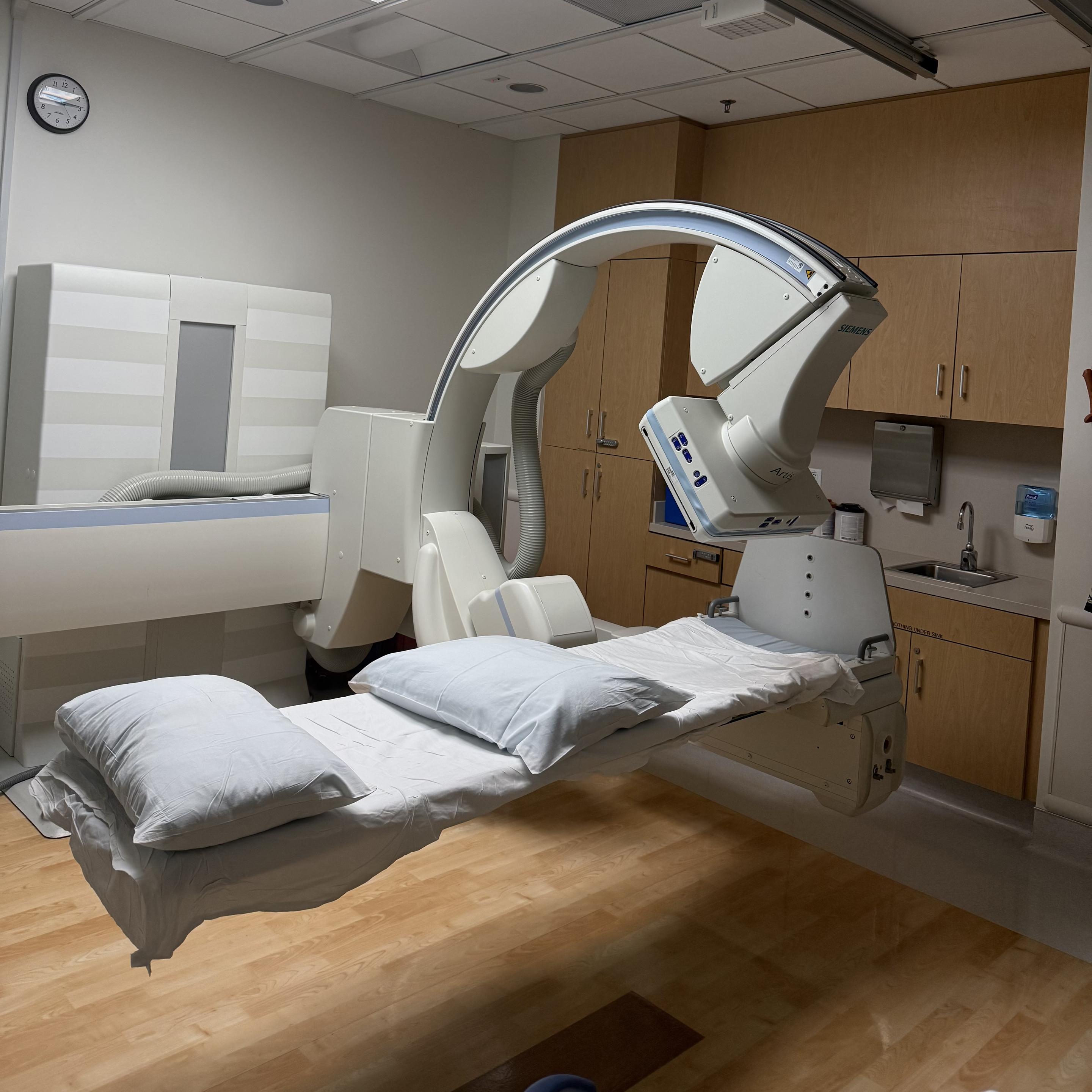 A fluoroscopy machine that I lie on for 30 minutes while 5ml of spinal fluid is removed and replaced with chemotherapy. This happens once or twice a week: it’s not painful, but it is nerve wracking since only a local anesthetic is used and I’m fully conscious during the procedure.

The machine itself is suspended in air with a straight beam that traverses the width of the room. On that beam is another circular beam where X-rays are emitted and collected. The doctor gets a live image that is used to guide their work.

It’s an impressive piece of engineering and medical science that’s saving my life.