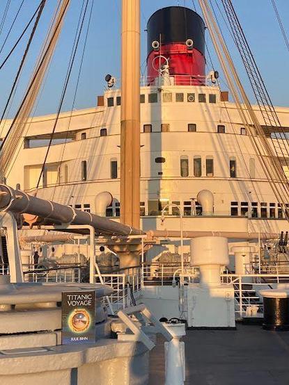 Titanic Voyage sitting on the Queen Mary, looking aft toward the bridge, a red-and-black funnel at the top. 