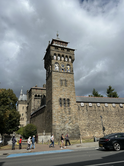 The tower in the picture is the Clock Tower of Cardiff Castle in Wales, an iconic landmark of the city. It was designed by William Burges and built between 1869 and 1873 in a French Gothic style, sitting on the remains of a Roman bastion. At 40 meters tall, it was the tallest building in Cardiff when it was finished and has seven floors. The facade features coats of arms and figures of Roman gods, and inside, you'll find fancy rooms like the winter and summer smoking rooms.
