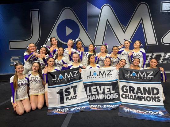 Ukiah High School varsity cheer team poses on a competition floor holding banners reading “1st Place,” “Level Champions,” and “Grand Champions” at a JAMZ Cheer & Dance event.