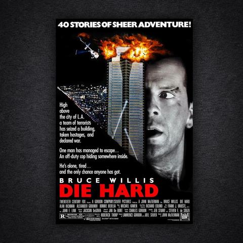 The original Die Hard film poster. Bruce Willis’s face fills the right side, looking tense and injured. At the centre, a tall skyscraper explodes near the top with flames and a helicopter overhead. The tagline reads “40 stories of sheer adventure!” with additional text describing a lone cop trapped inside the building.