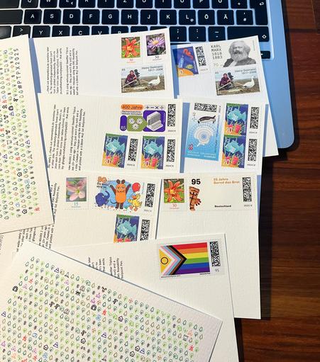 Photo of some post cards with lots of stamps on a laptop keyboard.