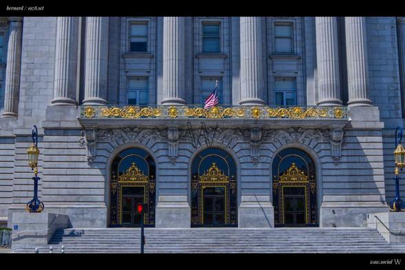 A cinematic color photo of San Francisco City Hall in California with a US flag in front.