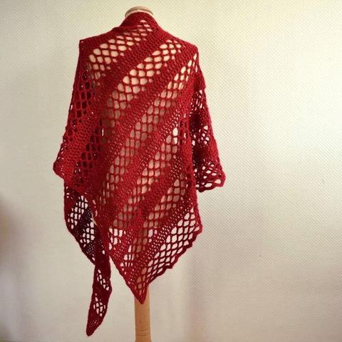 A triangular lace crochet shawl in red yarn, shown from the back on a mannequin, against a white background.