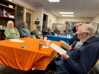 Photo of staff and board members around tables with orange and blue table cloths.