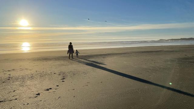 A woman and a child walk on a beach on the Oregon coast.