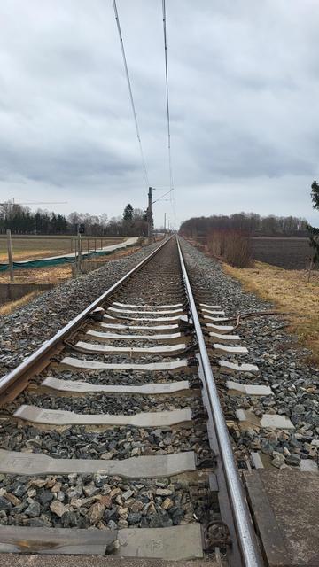 Eine Bahnstrecken vom unteren Bildrand bis in die Mitte des Bildes. Der Himmel hat grau.