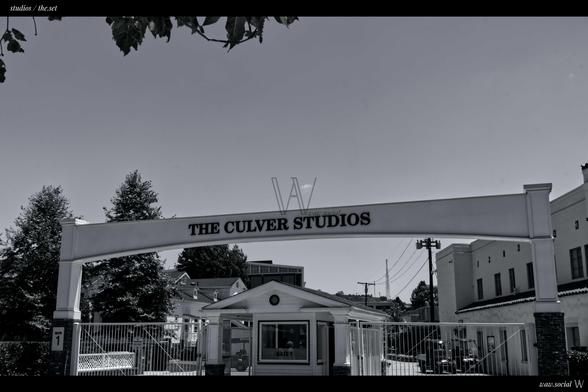 A black and white photo of The Culver Studios in Culver City, California framed by trees and buildings.