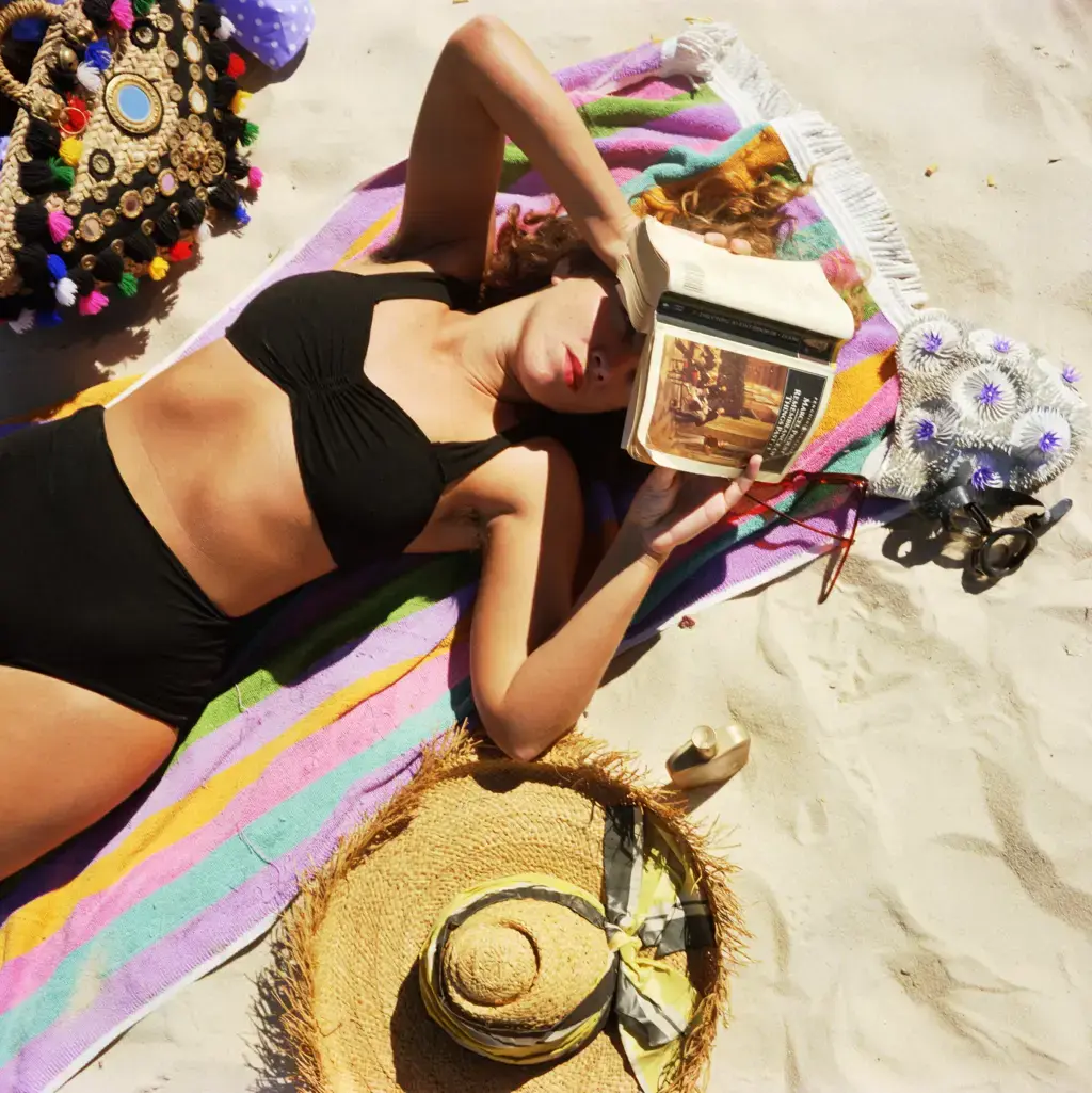 The Sunbather #1 1989 from the series Bondi: playground of the Pacific
In The Sunbather #1, Zahalka employs a sophisticated satirical detail to challenge the anti-intellectualism often associated with Australian beach culture. A young woman in a black bikini is depicted not engaging with the surf, but using a novel by Marcel Proust—Remembrance of Things Past—as a physical shield. The book is placed directly over her eyes to block out the glaring sun, a brilliant visual pun where "high culture" serves a purely utilitarian, defensive purpose.