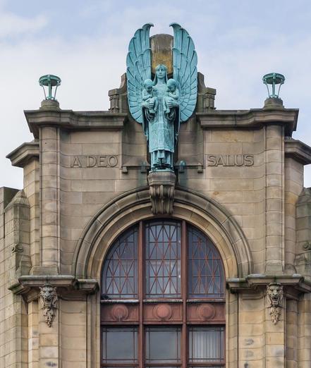 a photograph of the angel statue, it is blue-green, at the top of the entrance, it is done in an art deco / art nouveau style 