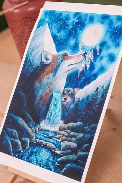 Zoom sur le Tirage d'art A4 open edition du loup 'Gardien des Rêves du Vivant' vue de profil. La vue de profil montre l'iridescence des pigments rehaussés sur la cascade et l'attrape-rêves. Ce tirage d'art est présenté sur un support, posé sur une table en bois.
