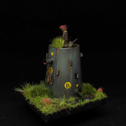 Grey metallic scratchbuilt tower with signage, rust and in overgrown foliage. 