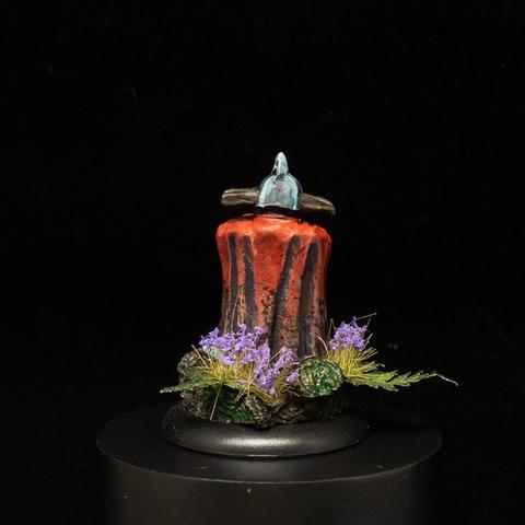 Dwarf in blue grey armour with a gold axe and red cloak, surrounded by foliage. Rear shot.