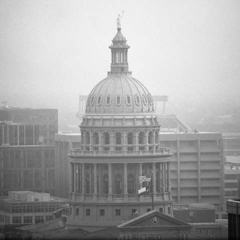 A black-and-white film photo. The Texas State Capitol is seen surrounded by fog in downtown Austin, Texas. Saturday, February 28, 2026.