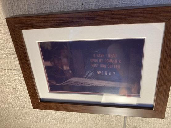 A photograph of a small framed eink display which is displaying a (dithered) frame from the film hackers.