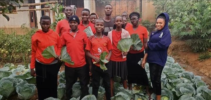 Young children together with the representatives from Fill the Empty Stomachs Farming Initiative in one of the local farmer's gardens after harvesting some vegetables.
