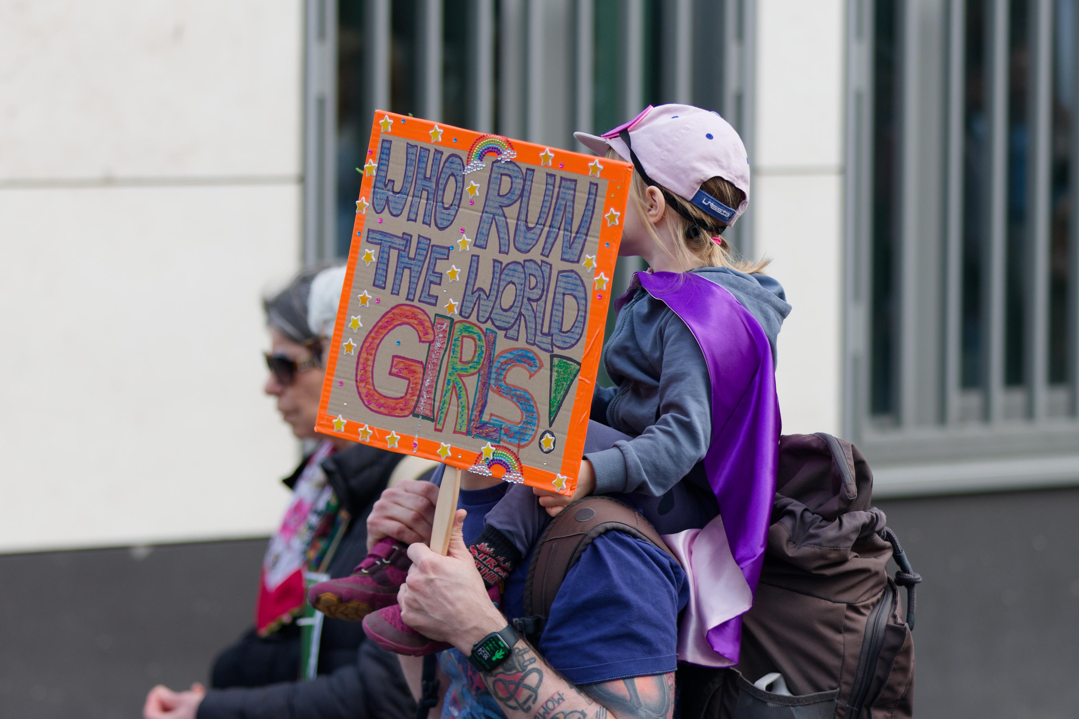 Schild mit dem Text „Who Run The World Girls!“.