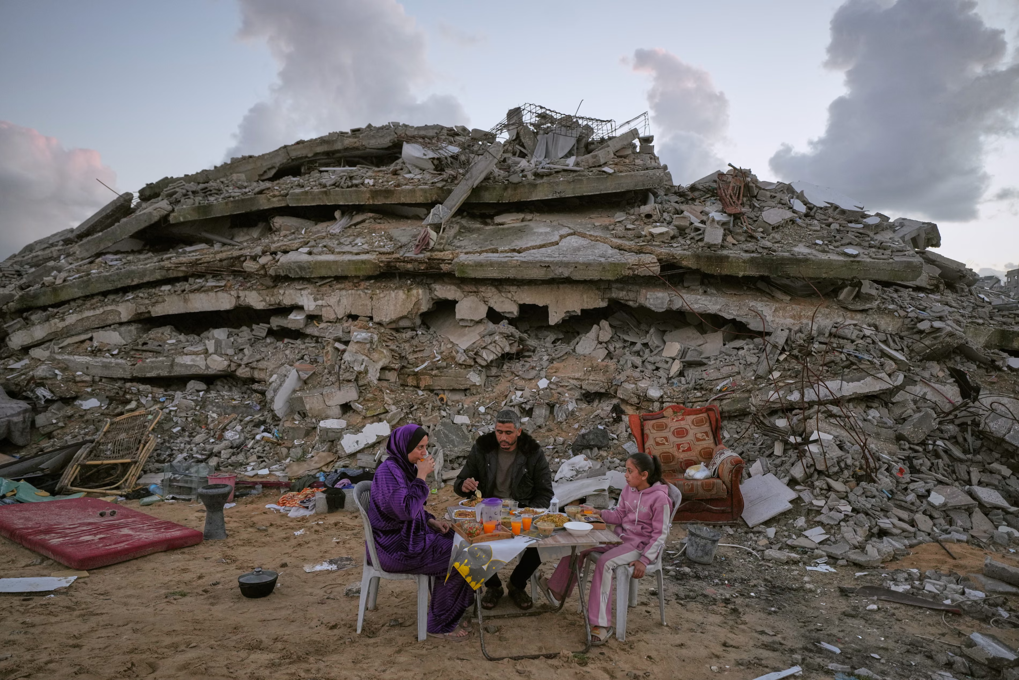 A family at a Ramadan table sitting in front of pancaked building.