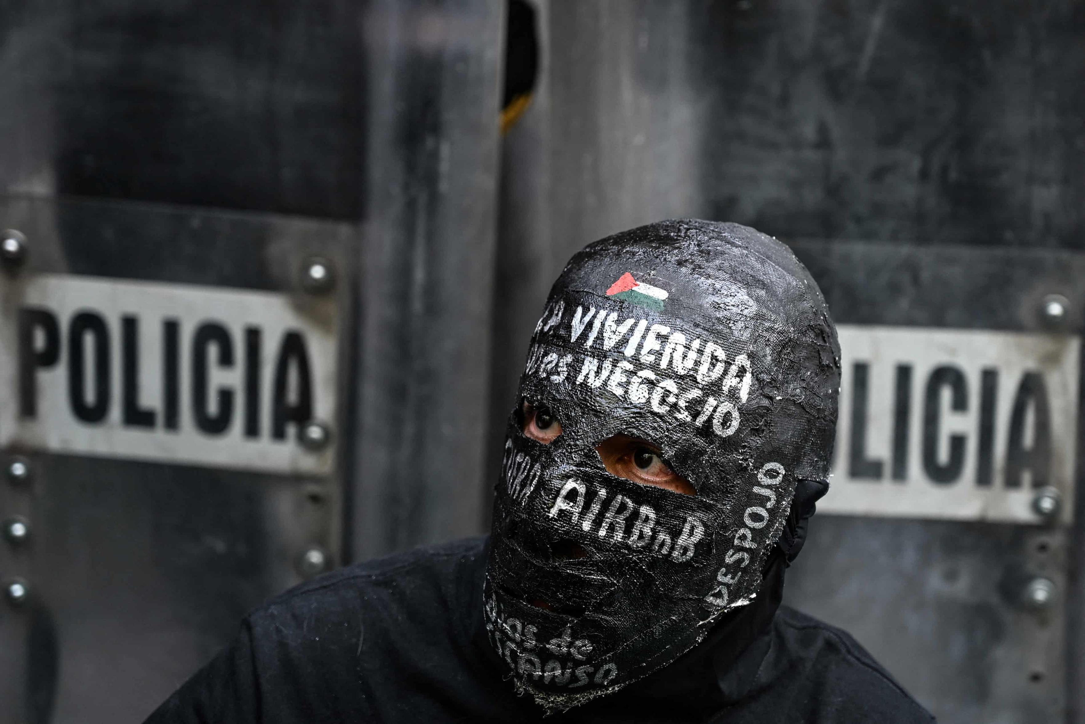 A demonstrator wears a mask reading ‘housing is not a business, Airbnb out’