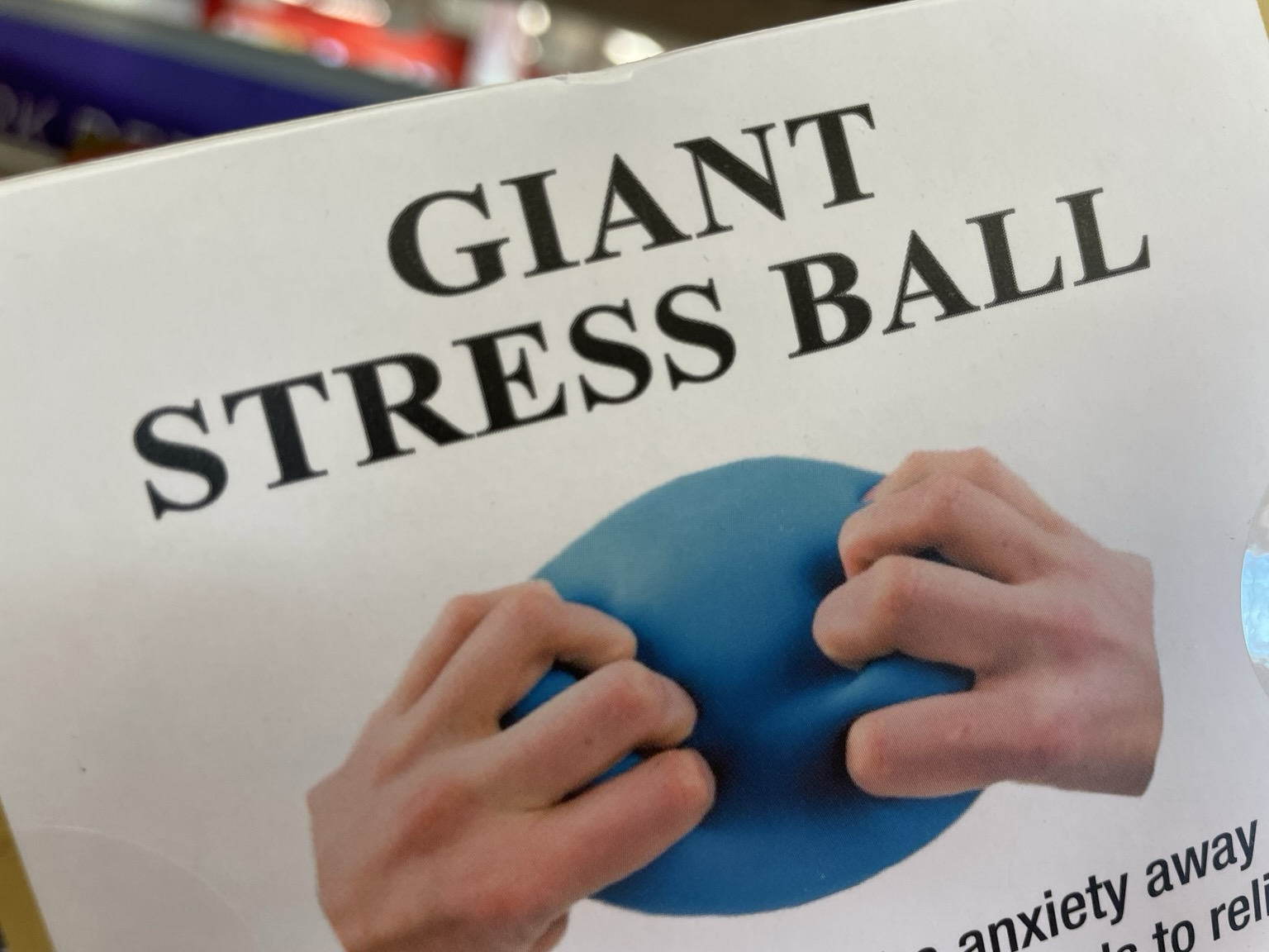 A label for Giant Stress Ball. Underneath is an image of two hands gripping a blue stress ball in a manner reminiscent of the goatse meme from many years ago