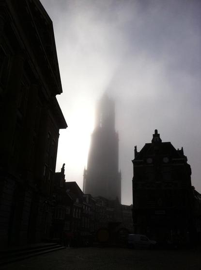Silhouette of the Dom Tower in Utrecht in the mist, with strong backlighting from the sun