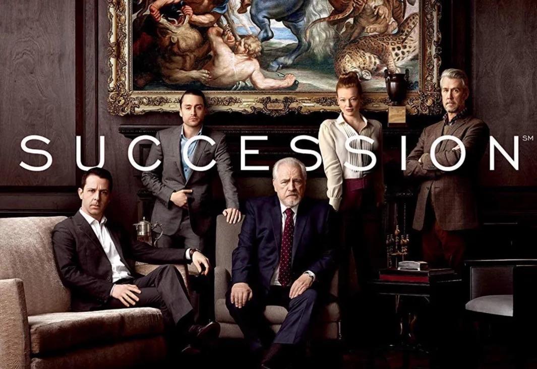 Promo photo for succession. Father is sitting in the middle with his kids surrounding him. There's a painting in the background.