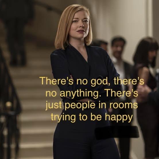 Shiv, woman with light brown hair medium length wearing black suit and folding her arms. "There's no god, there's no anything. There's just people in rooms trying to be happy"