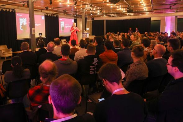 Prof. Dr. Alena Buyx presenting a keynote talk on stage at the BaselOne 2025 developer conference in Markthalle Basel, with a full audience of developers and architects watching the session.