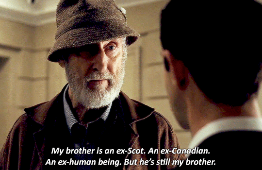 Ewan wearing a hat and overcoat. Over the shoulder shot. "my brother is an ex-Scott. An ex-Canadian. An ex-human being. But he is still my brother."
