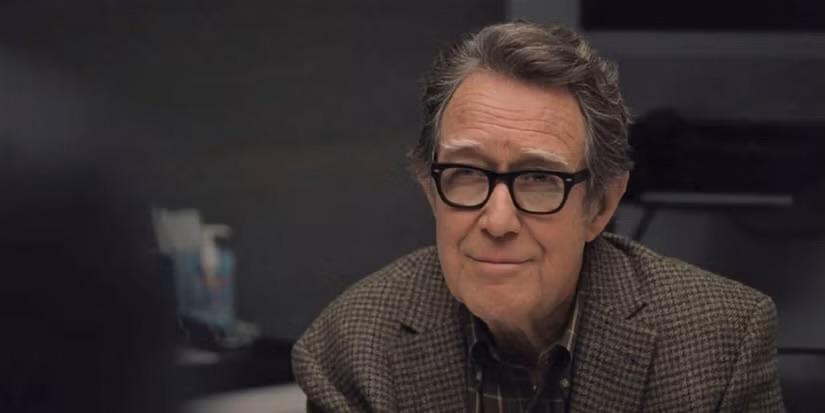 Sandy, man, older. Black glasses. In a brown blazer.