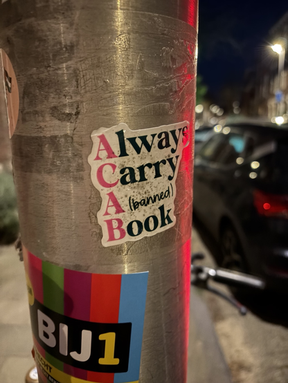 2 stickers op lantaarn paal
Always
Carry
A(banned)
Book
Met de hoofdletters in roze
en
BIJ1
