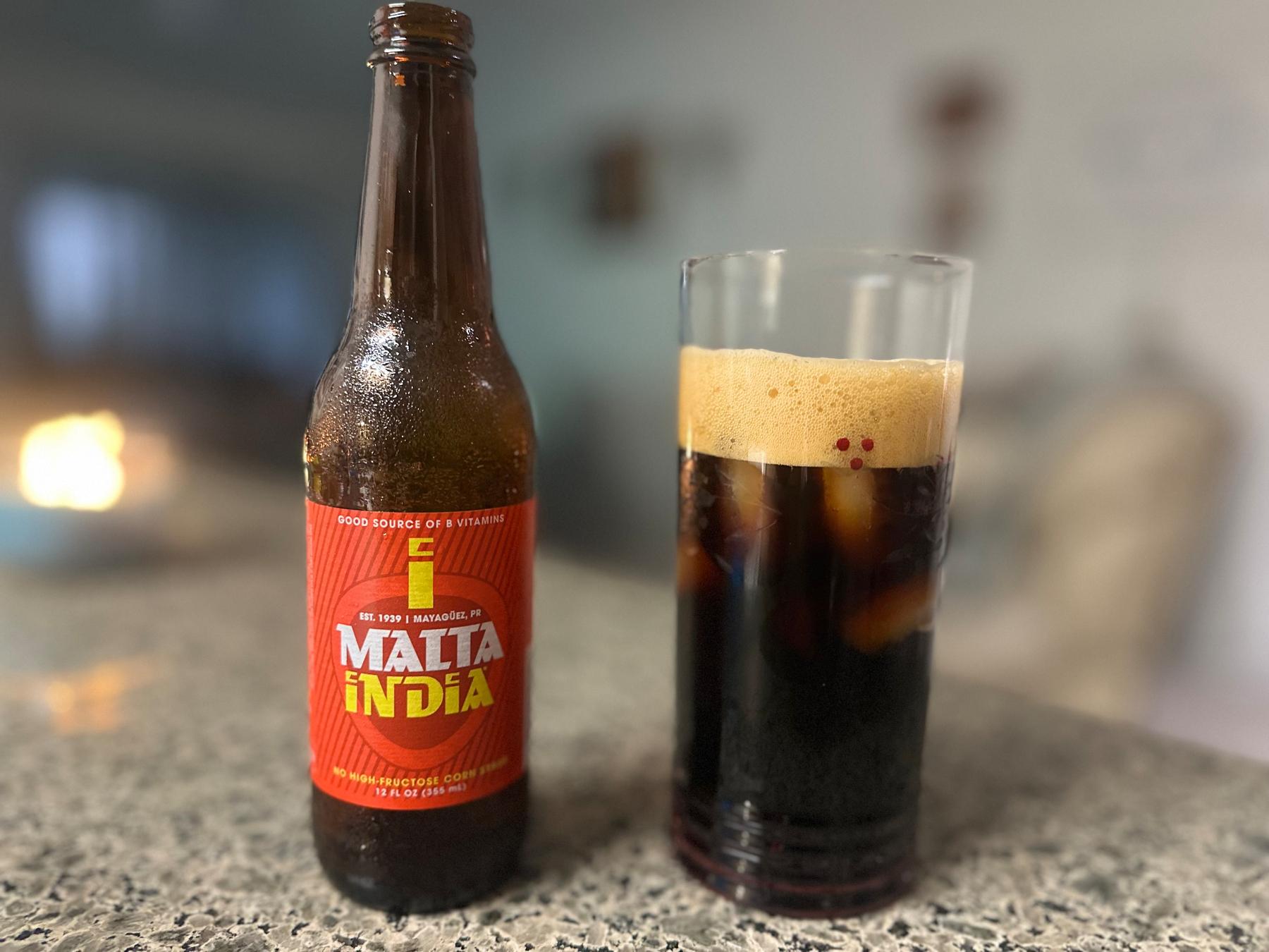 Bottle with red label "Malta India" and a glass with a substance in it that looks a little like Guinness beer. 