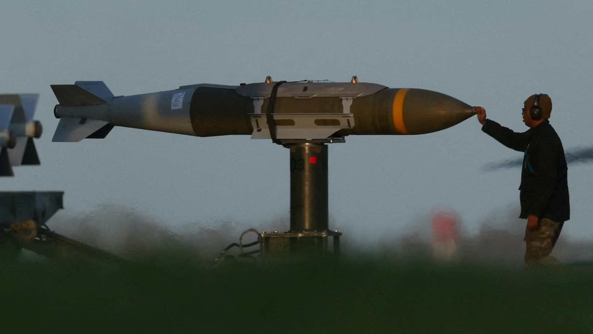 A man touches the tip of a missile, as if it was the nose of a dog.