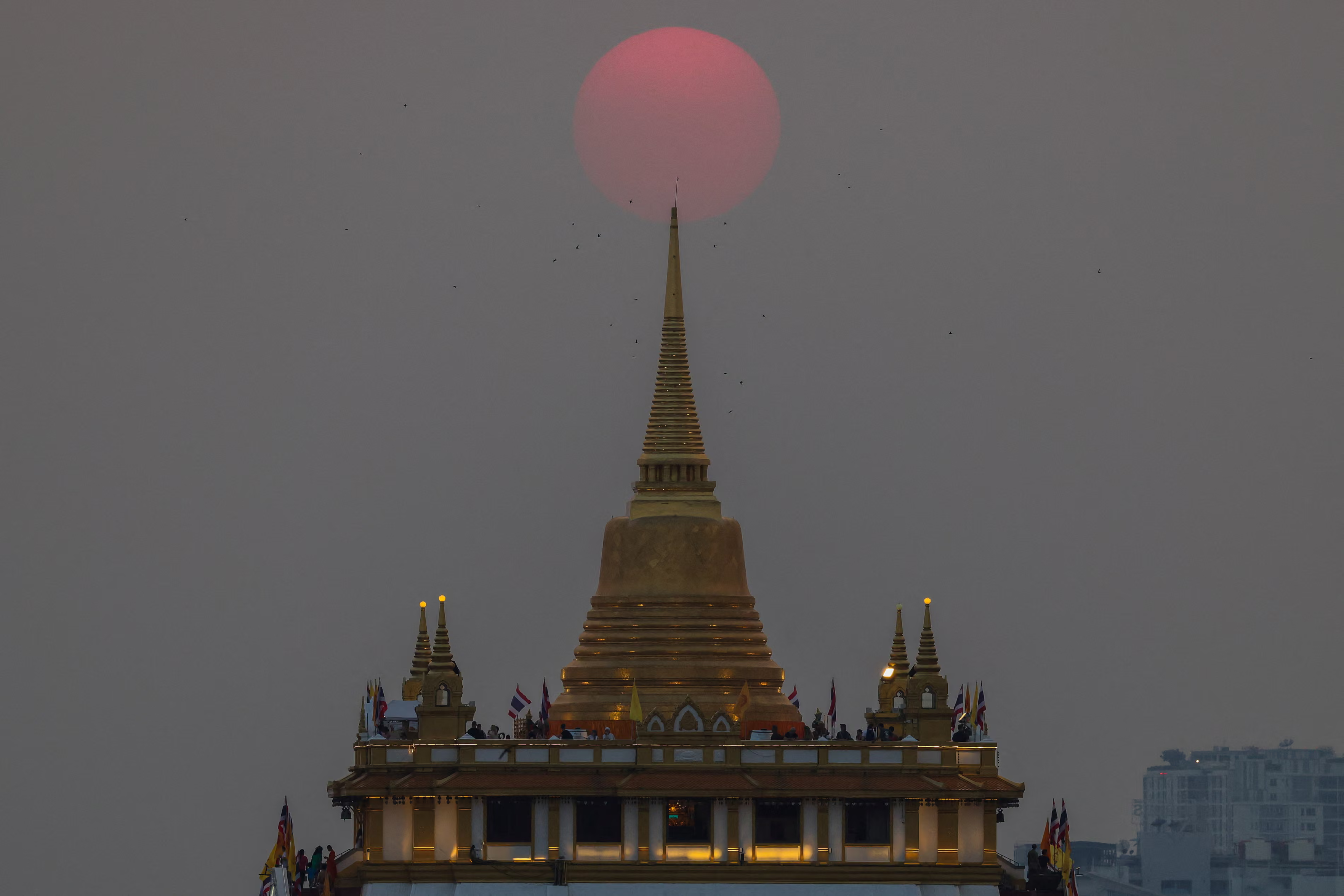 The sun sets behind Wat Saketโs golden apex.